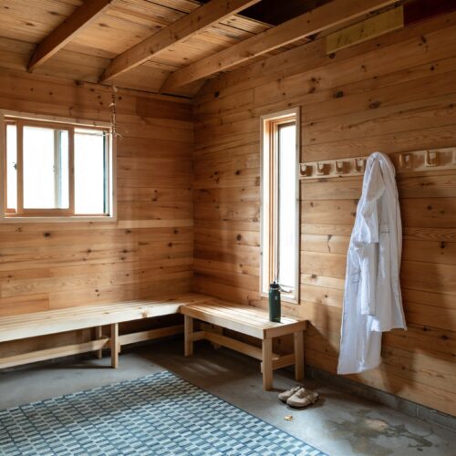 Thoughtful sauna entry: robes, benches, cubbies, and plenty of pegs for towels and gear.