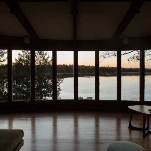 Floor-to-ceiling windows frame quiet Northwoods water from sunrise to dusk.
