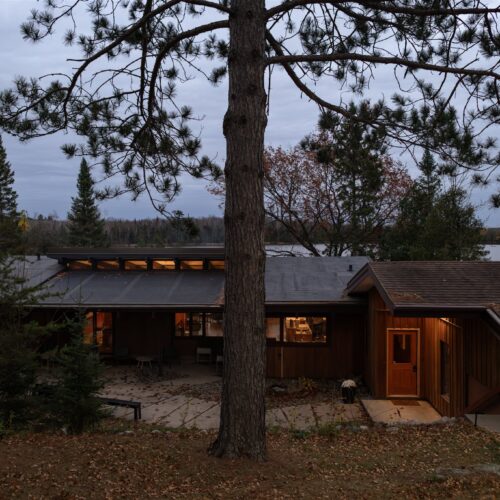 The home’s mid-century lines shine as the evening settles in.